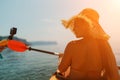 A woman wearing a straw hat is paddling a canoe on a sunny day. Scene is relaxed and carefree, as the woman enjoys her Royalty Free Stock Photo