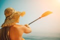 A woman wearing a straw hat is paddling a canoe on a sunny day. Scene is relaxed and carefree, as the woman enjoys her Royalty Free Stock Photo