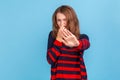 Woman wearing striped sweater grabbing nose, grimacing in disgust and showing stop gesture Royalty Free Stock Photo