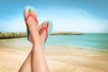 Woman wearing stylish flip flops resting on sandy beach and enjoying beautiful seascape, closeup