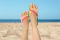 Woman wearing stylish flip flops resting on sandy beach and enjoying beautiful seascape, closeup