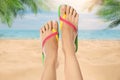 Woman wearing stylish flip flops resting on sandy beach and enjoying beautiful seascape, closeup