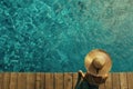 woman wearing sun hat on a wooden pier view from above, turquoise water swimming pool. Summer concept Royalty Free Stock Photo