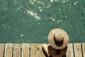 woman wearing sun hat on a wooden pier view from above, turquoise water swimming pool. Summer concept Royalty Free Stock Photo