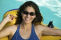 Woman wearing sunglasses lying on inflatable raft in swimming pool portrait. Royalty Free Stock Photo