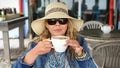 Woman wearing sunhat and sunglasses, drinking coffee from a huge coffeecup Royalty Free Stock Photo