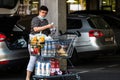 Woman wearing surgical mask with shopping cart full of goods, putting groceries in car trunk. Bucharest, Romania, 2020 Royalty Free Stock Photo