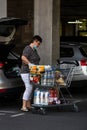 Woman wearing surgical mask with shopping cart full of goods, putting groceries in car trunk. Bucharest, Romania, 2020 Royalty Free Stock Photo