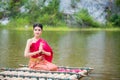 Woman wearing Thai traditional dress sitting on bamboo raft Royalty Free Stock Photo