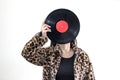 Woman wearing tiger pattern clothes holding old vinyl retro record music audio look like a head on background