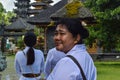 A Woman Wearing Traditional Balinese Smiling And Turning Around, Waiting For Prayer Ceremony