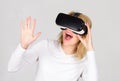 Woman wearing virtual reality goggles in grey background. Woman using virtual reality headset. Confident young woman