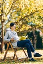 Woman wearing warm knit clothes drinking a cup of hot tea or coffee and reading a book outdoors in sunlight - season, literature Royalty Free Stock Photo