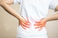 A woman wearing a white shirt feels a back pain. I work for many hours