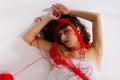 Woman white silk nightie laying white floor red woolen thread