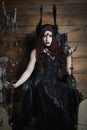 Woman wearing a winged headdress and sitting in a black, Gothic throne Royalty Free Stock Photo