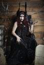 Woman wearing a winged headdress and sitting in a black, Gothic throne Royalty Free Stock Photo