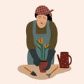 Woman wearing working robe, caring flowers in pots, planting strelitzia flowers, agriculture at home concept, stay home gardener