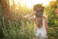 Young woman wearing wreath made of beautiful flowers outdoors on sunny day, back view Royalty Free Stock Photo