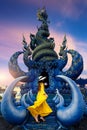 Woman wearing yellow dress at Wat rong suea ten or blue temple in Chiang rai, Thailand