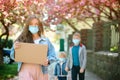 Woman wears face mask outdoors. Female holding empty board for text during quarantine. Family wearing safety masks walk on street