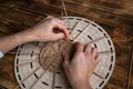 Woman weaves basket of paper tubes on wooden table. Process of weaving a decorative basket from tubes twisted from paper