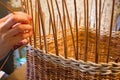 A woman weaves a basket from a paper vine.