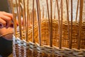 A woman weaves a basket from a paper vine.