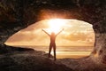 Woman welcomes the sunrise in a cave