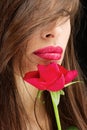 Woman and wet red rose near her lips