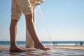 Woman wetting her feet with a shower to clean them from the sand