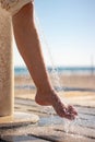 Woman wetting her feet with a shower to clean them from the sand