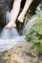 Woman wetting her feet in a stream.