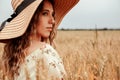 Woman wheat field nature. Happy young woman in sun hat in summer wheat field at sunset. Copy space, sunset, flare light