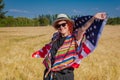 Woman in a wheat field with a USA flag