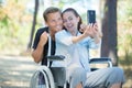 Woman in wheelchair and boyfriend taking selfie with smartphone Royalty Free Stock Photo