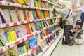 A woman in a wheelchair chooses a book for a child in the children`s department of the store. Royalty Free Stock Photo