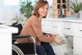 woman in wheelchair doing housework in kitchen and smiling Royalty Free Stock Photo