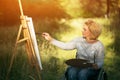 Woman in wheelchair drawing on easel outside Royalty Free Stock Photo