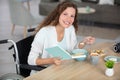 woman in wheelchair at home reading at table Royalty Free Stock Photo