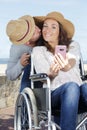 Woman in wheelchair and husband taking selfie outdoors Royalty Free Stock Photo