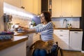 Woman in wheelchair in kitchen at home Royalty Free Stock Photo