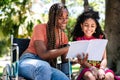 Woman in a wheelchair reading a book with her daughter. Royalty Free Stock Photo