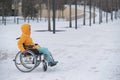 Woman in wheelchair relaxing in winter park.