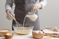 Woman whisking crepe batter in glass bowl at white wooden table, closeup