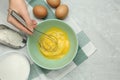 Woman whisking eggs in bowl at grey table, top view. Space for text