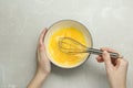 Woman whisking eggs in bowl at grey table, top view