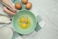 Woman whisking eggs in bowl at light grey table, top view. Space for text