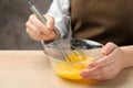 Woman whisking eggs in glass bowl at table, closeup