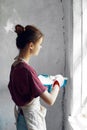 Woman in a white apron paints a window in a house interior renovation Royalty Free Stock Photo